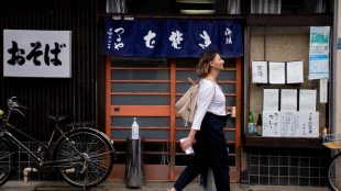 a woman walking down the street in front of a store