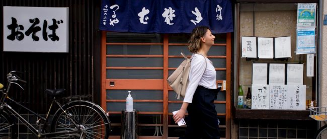 a woman walking down the street in front of a store
