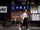 a woman walking down the street in front of a store