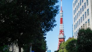 A city street with a red and white tower in the background