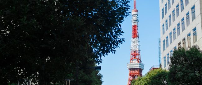 A city street with a red and white tower in the background
