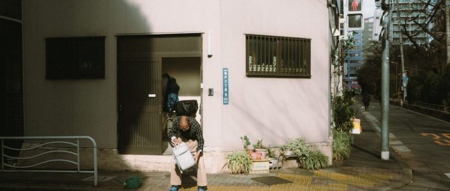 Man sitting on a curb reading a newspaper.