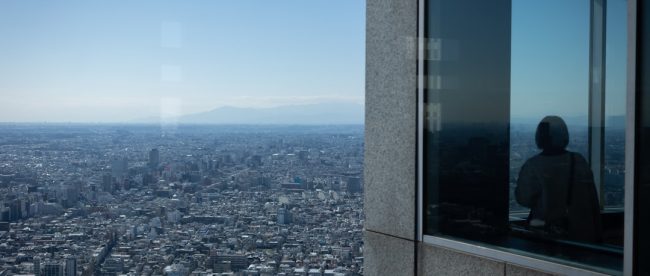 a person looking out a window at a city